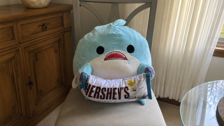 a shark snaclwe plush with a plush hershey bar in a dining chair
