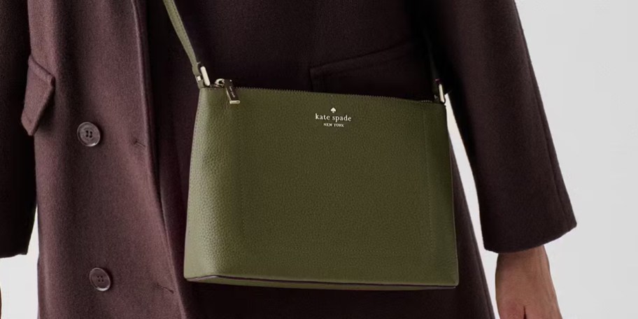 person wearing dark green crossbody bag and purple jacket