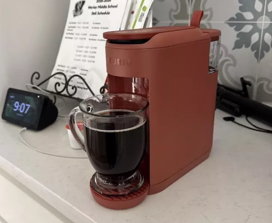 rust colored keurig mini mate on kitchen counter with glass of coffee
