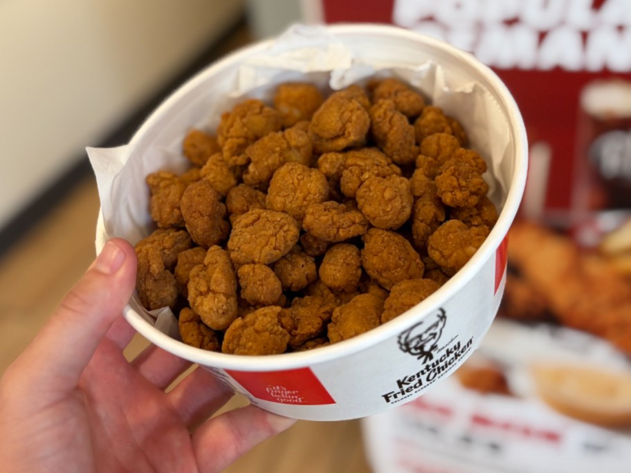 man holding bucket of popcorn chicken