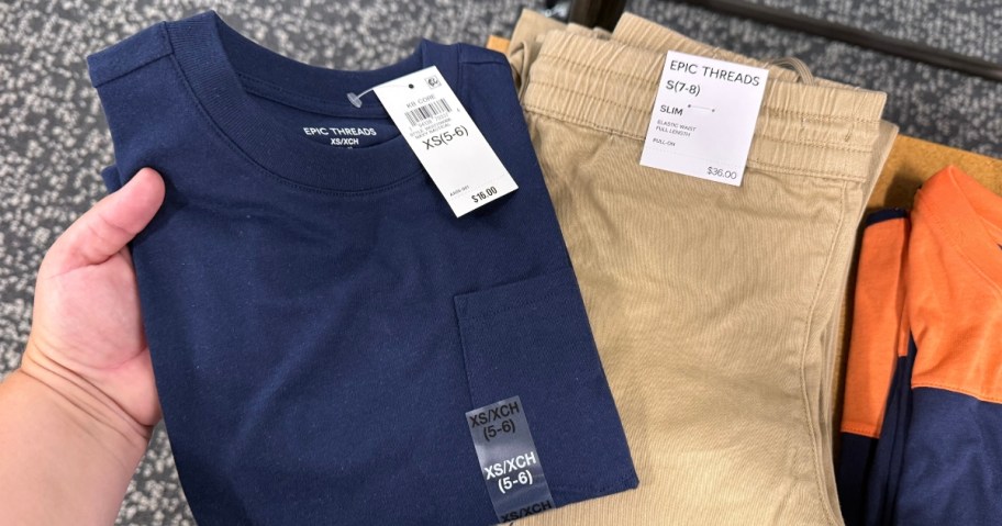 hand holding a boys t-shirt next to pants