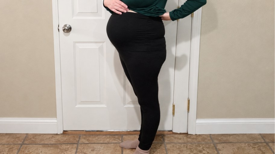 a woman wearing black maternity leggings and a green shirt