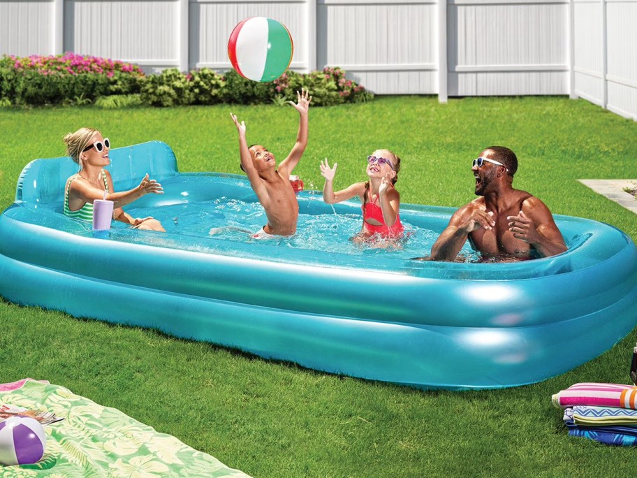 people hanging out in flatable pool in yard 