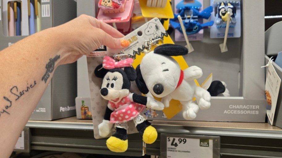 a hand holding two character plush bag charms
