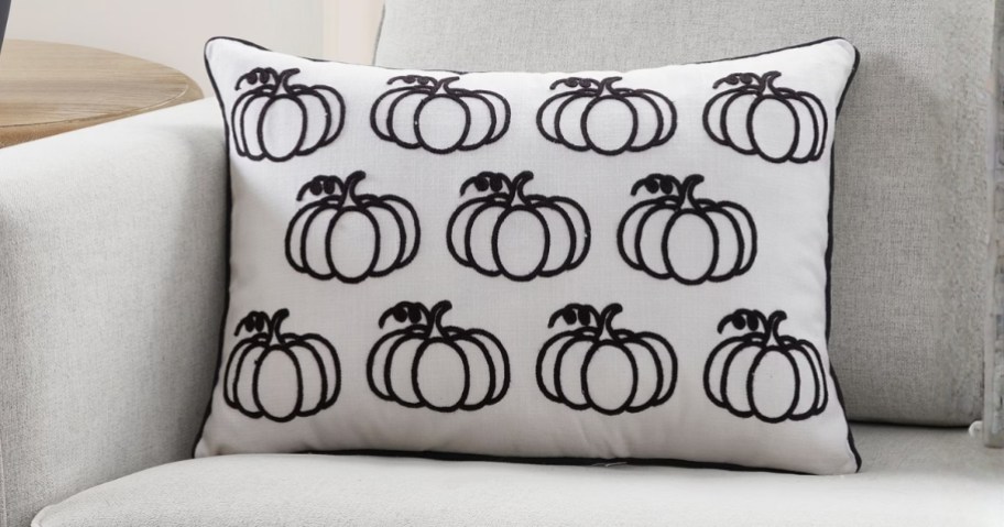 a white and black pumpkin Halloween pillow on a sofa