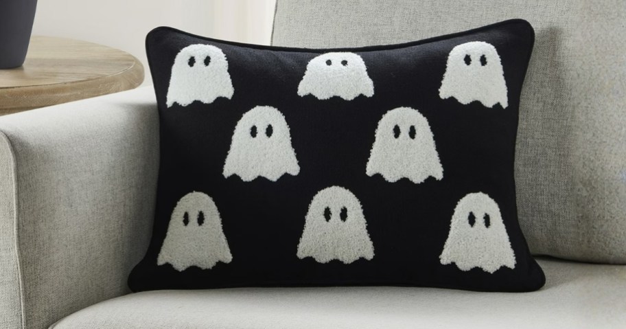a black and white ghost Halloween pillow on a sofa