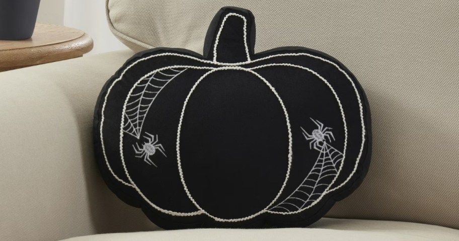 a black pumpkin Halloween pillow on a sofa