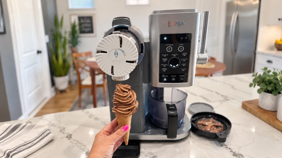 ninja swirl icream maker and a hand holding a chocolate soft serve cone