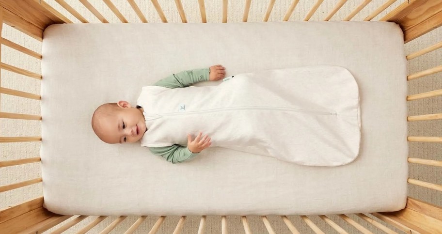 baby laying in crib wearing wearable blanket
