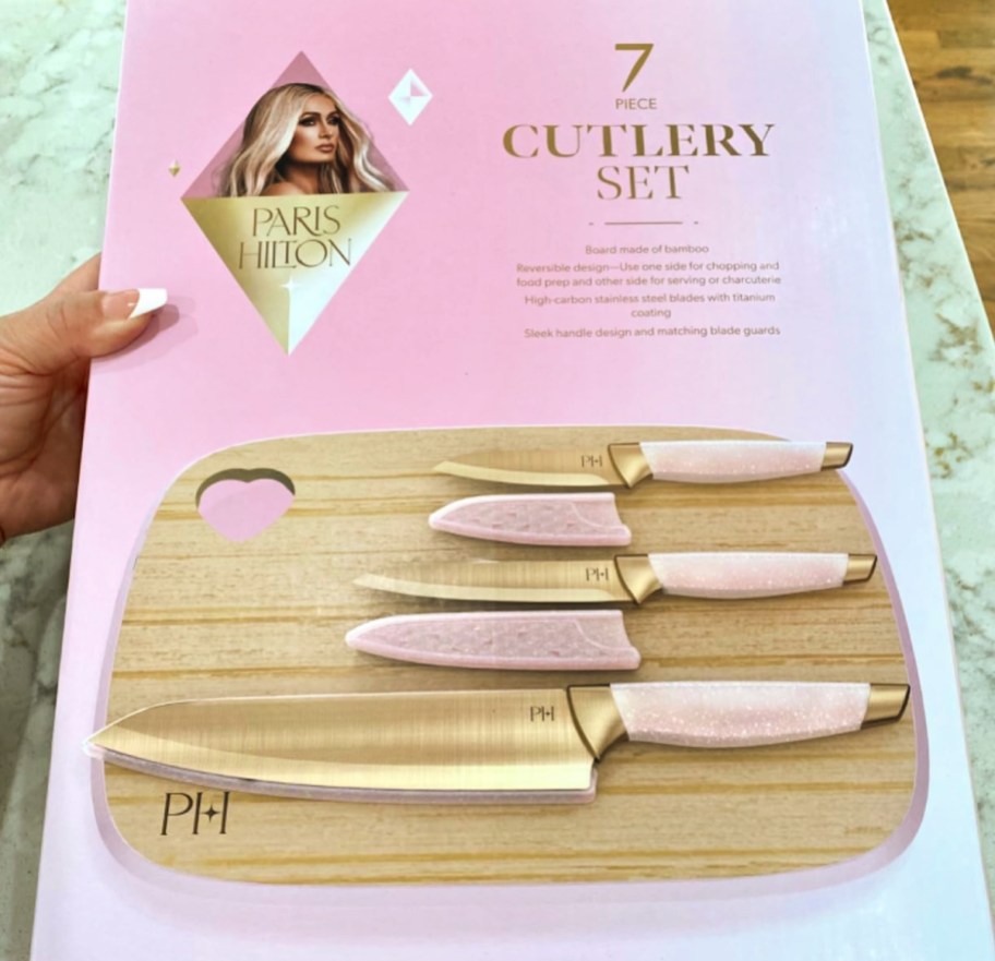 hand holding a box with pink knives and a bamboo cutting board