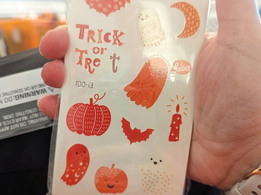 hand holding orange halloween tattoos 