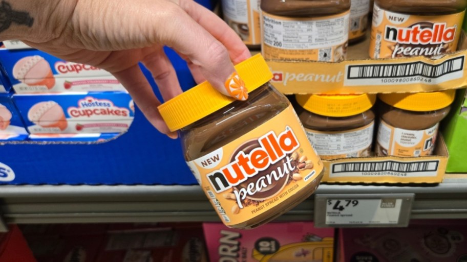 a hand holding a jar of peanut nutella
