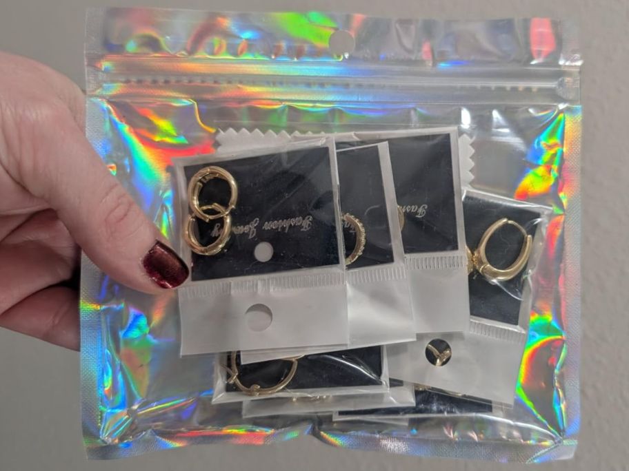 hand holding pouch with gold hoops in there