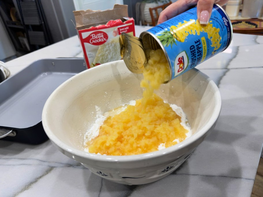 pouring canned pineapple into a mixing bowl