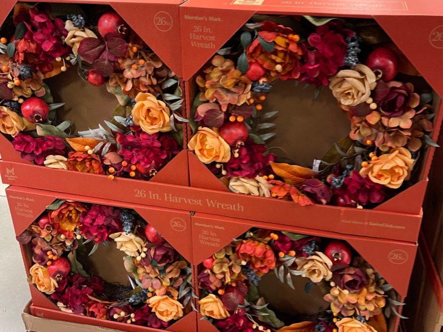 Four stacked boxes of Member's Mark 26-inch harvest wreaths featuring autumn-colored flowers, berries, and foliage.