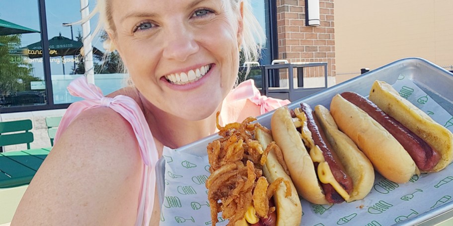 woman holding three hot dogs
