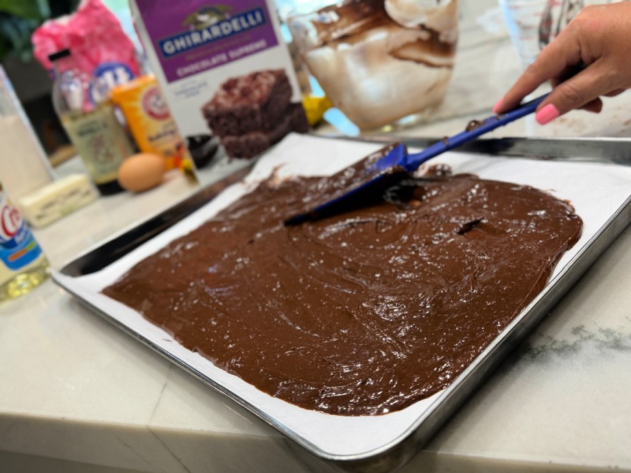 spreading brownie batter on a sheet pan