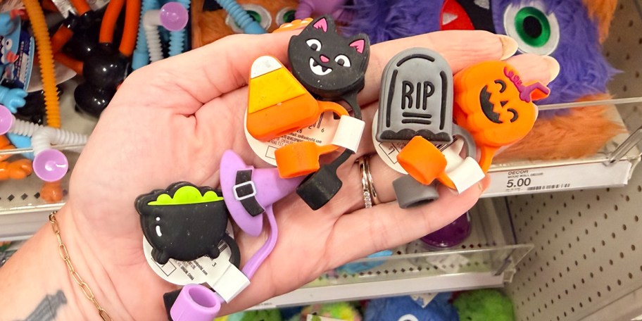 hand holding cat, witch, candy corn, and cauldron toppers 