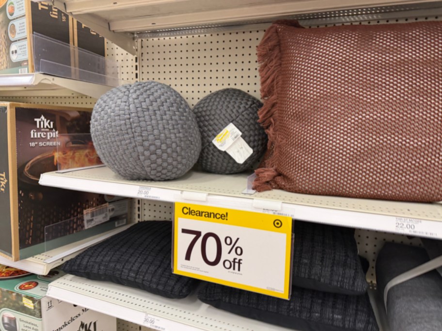 A Target store shelf displaying assorted decorative pillows and a large yellow sign advertising 70% off clearance.