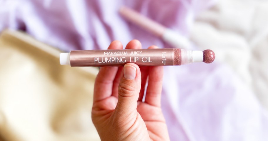 hand holding tarte Maracuja Juicy Plumping Lip Oil