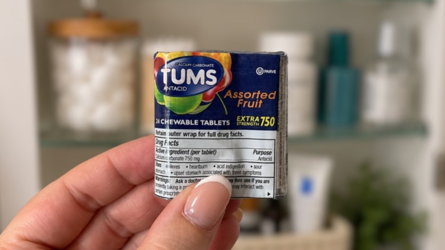 a hand holding a 3 pack of tums
