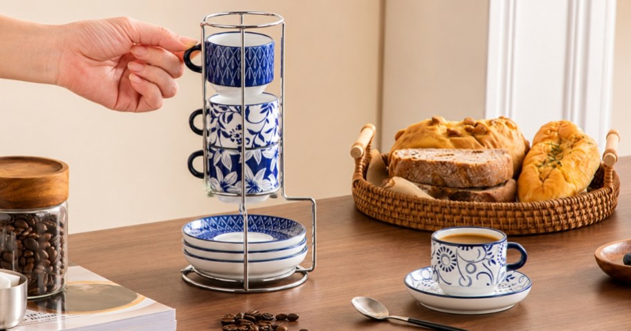 hand reaching for a blue and white espresso cup in a stand with saucers