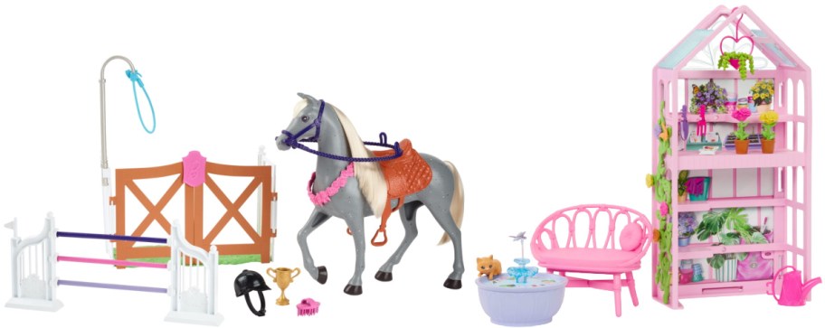 A Barbie equestrian playset featuring a gray horse with a saddle and bridle, a jumping hurdle, fencing with a gate, a riding helmet, a trophy, a brush, a small fountain with a cat, a pink bench, and a tall pink greenhouse shelving unit filled with plants and gardening supplies.