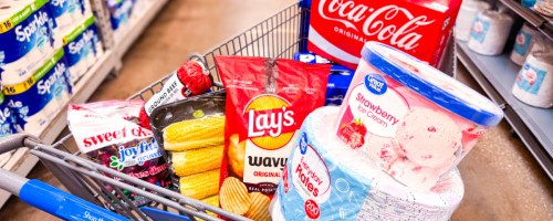 walmart cart full of groceries and paper goods in a store aisle