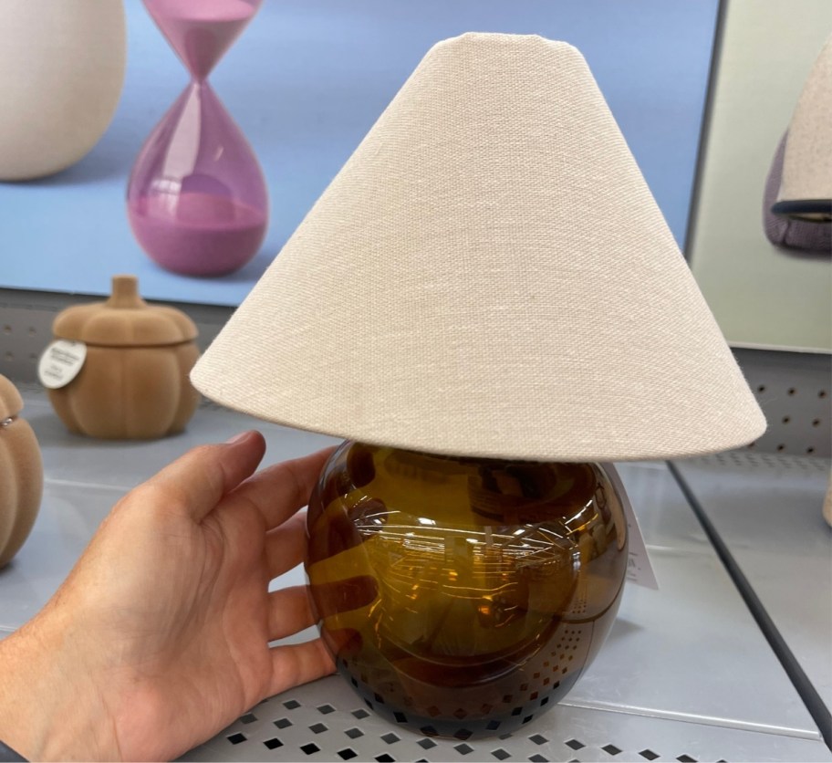 womans hand touching the amber base of a rechargeable dimmable table lamp