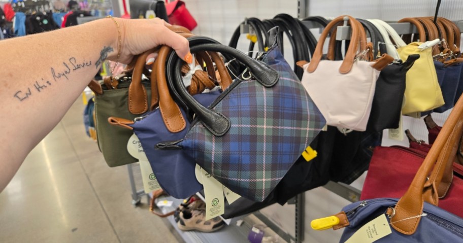 hand holding several mini tote bags in a store