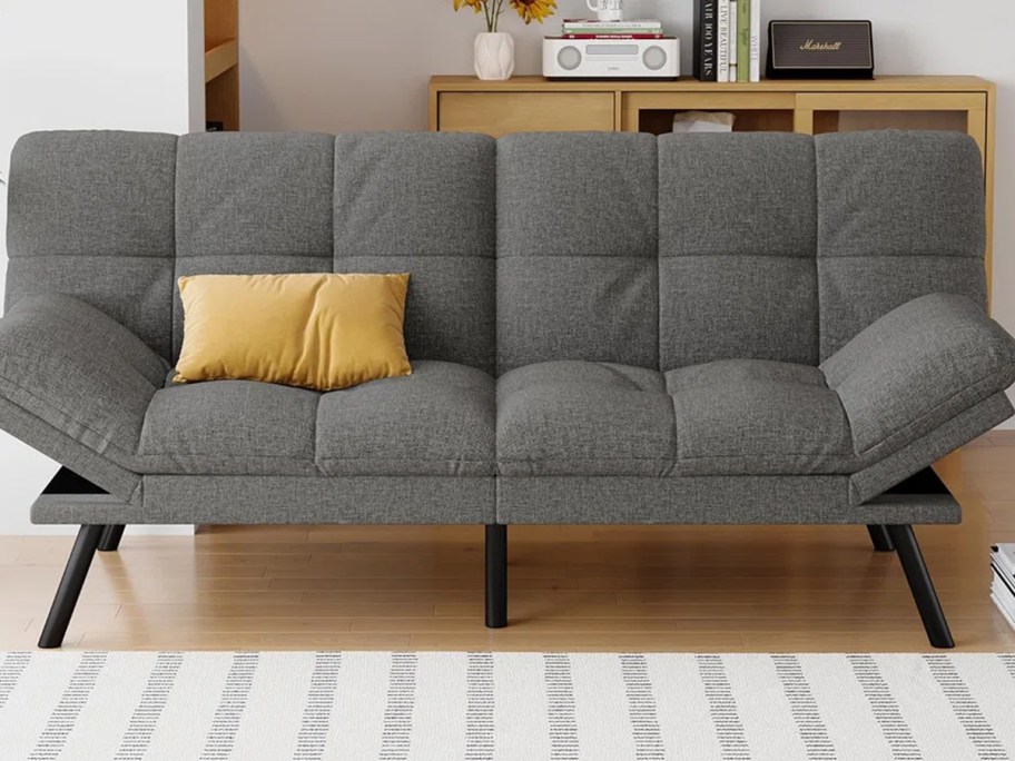 gray futon bed with yellow pillow 