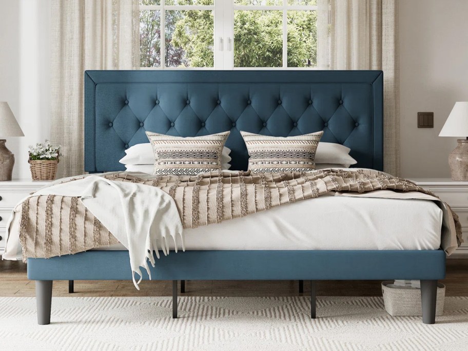 blue tufted bed with tan bedding on top 