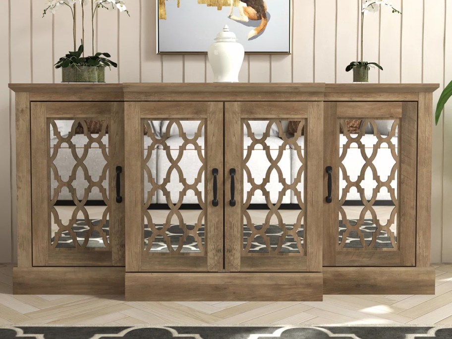 wood and mirror sideboard table with vase and plants on top 