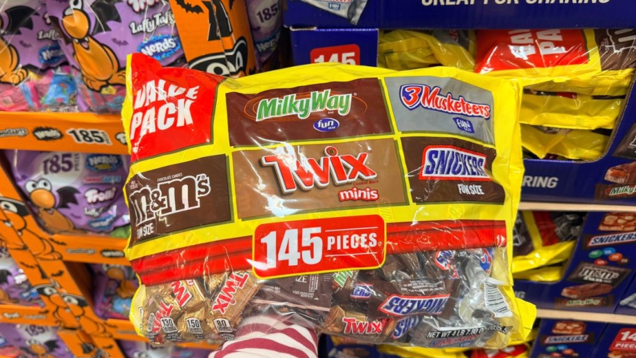 a womans hand holding a bag of assorted chocolate candies
