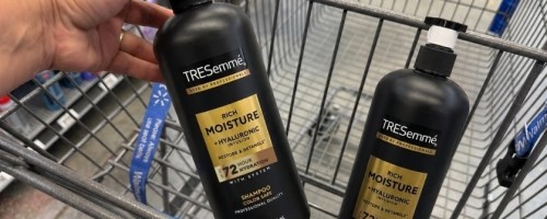 hand pulling a bottle of shampoo out of a walmart store cart