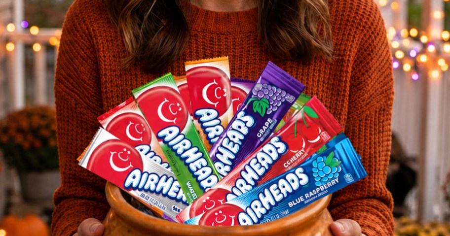 woman holding an orange bowl full of airheads bars