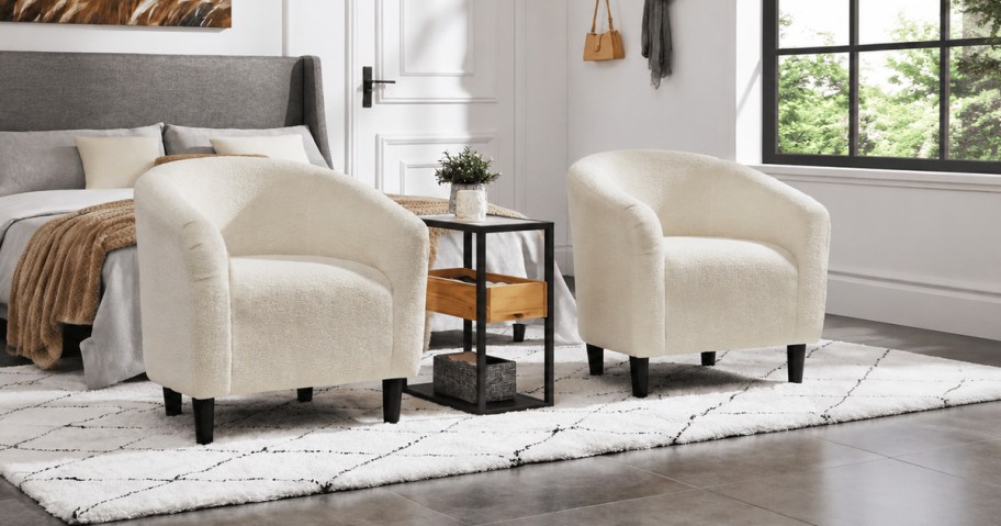 Two Alden Design ivory upholstered barrel accent chairs styled in a bright bedroom