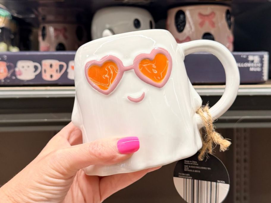 Hand holding an ALDI Halloween Ghost Mug with heart-shaped sunglasses on