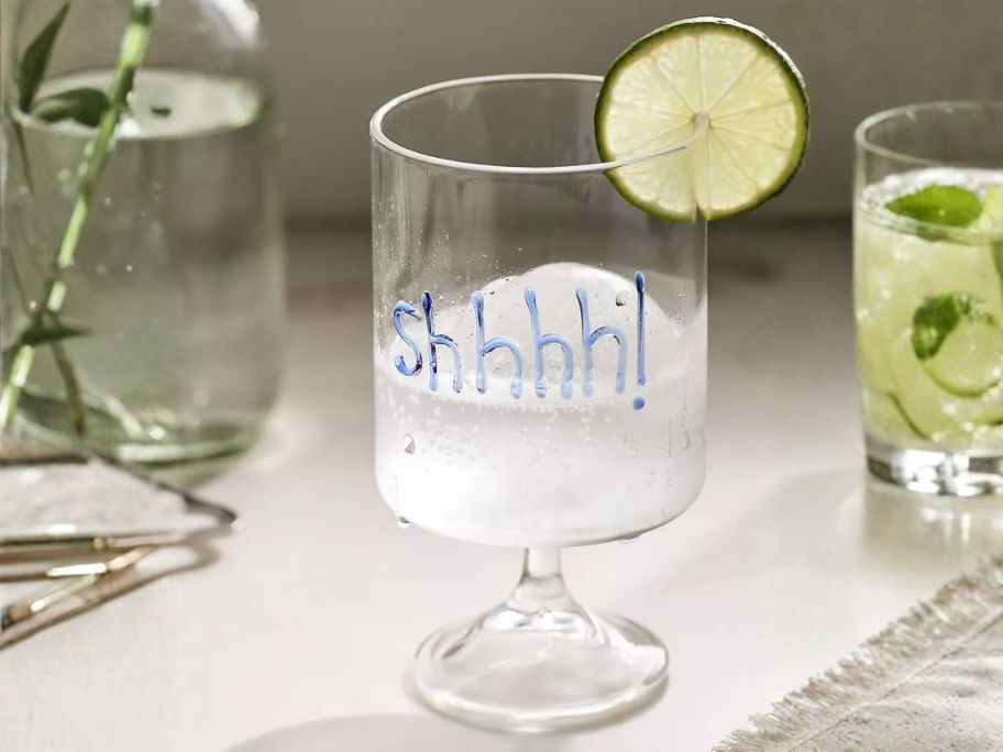 Anthropologie Word Play Wine Glass with "Shhhh" written on it on table