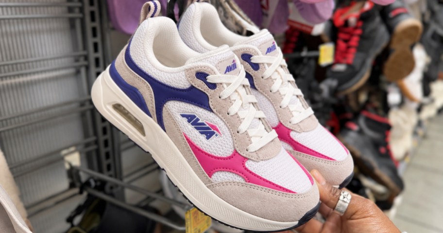 hand grabbing a pair of sneakers from store display wall