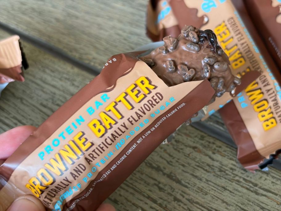 an open barebells protein bar in hand