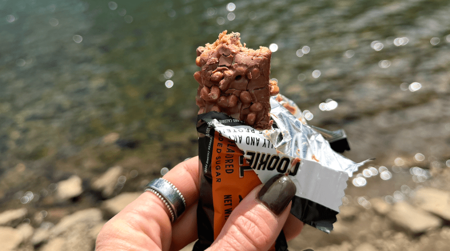 hand holding protein bar in front of water
