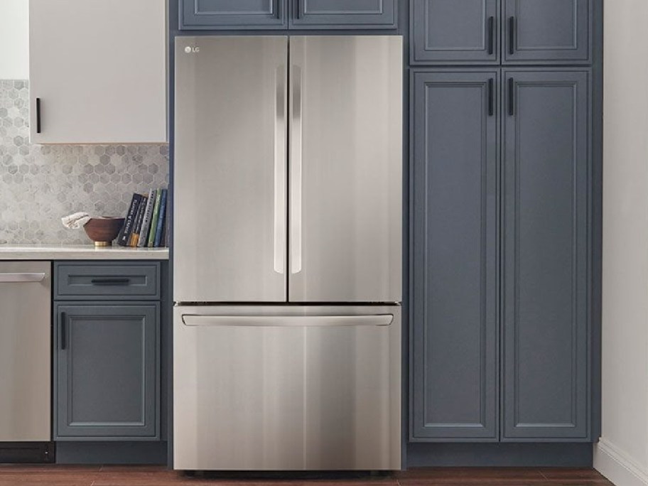 An LG stainless steel French door refrigerator installed in a kitchen with dark blue cabinetry.