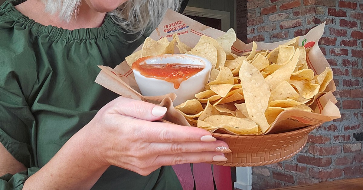 Woman holding up basket of Chili's chips and salsa