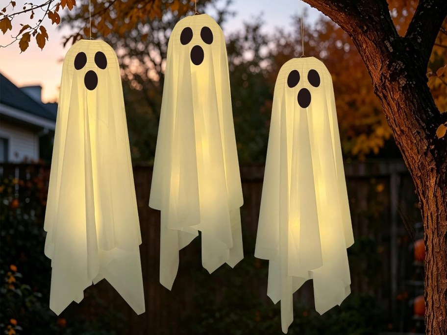 three halloween ghosts hanging from a tree
