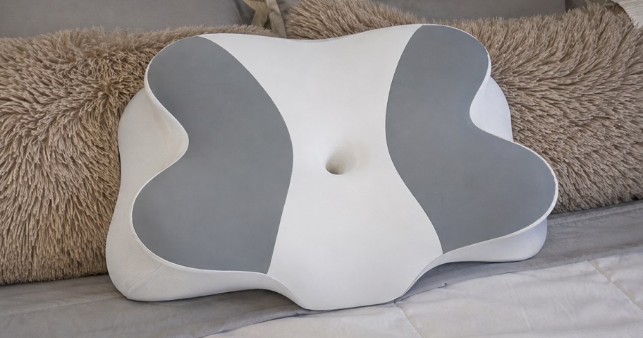 white and grey cervical pillow on a bed