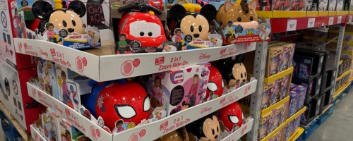 A store display shelf stocked with various Disney and character 2-in-1 Zoom Ride-On toys, including Mickey Mouse, Cars, Spider-Man, and Bullseye styles.
