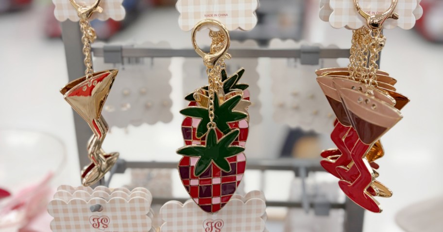 Packaged Frasier Sterling bag charms featuring cocktail and strawberry designs hanging on a retail display rack.