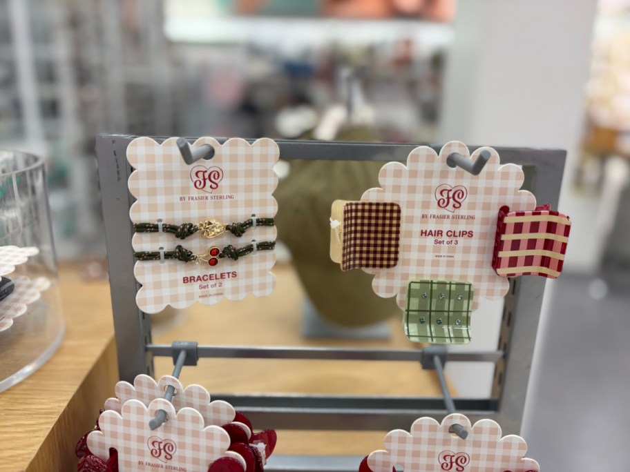Packaged Frasier Sterling accessories including a set of two bracelets and a set of three plaid hair claw clips displayed on a retail rack.