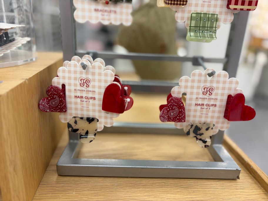 Two packaged sets of Frasier Sterling heart-shaped mini hair claw clips displayed on a retail shelf.